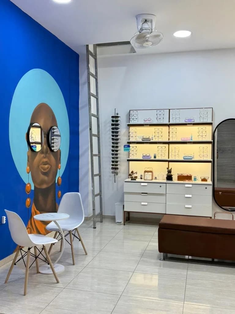 Zona de espera y atención al cliente en Optilux Valledupar con mural artístico moderno en pared azul.