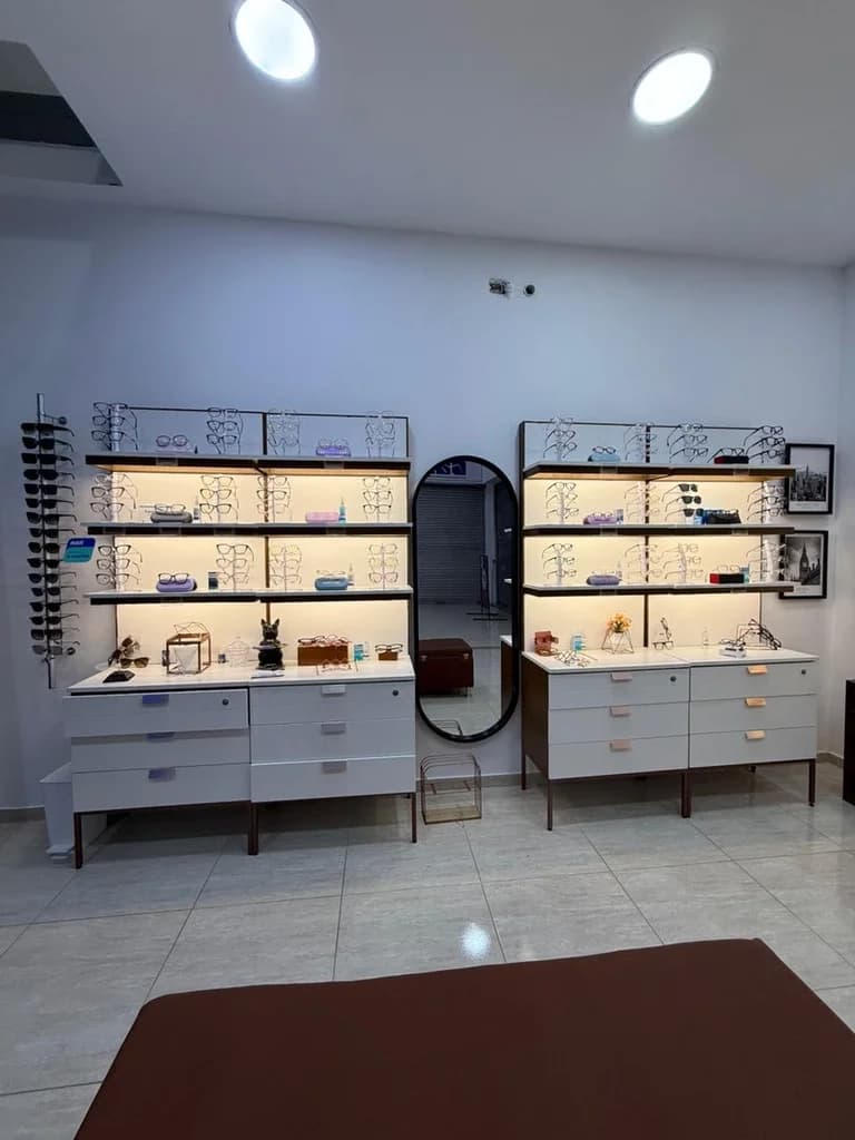 Exhibición de monturas de gafas graduadas y de sol en Optilux Valledupar con estanterías modernas e iluminadas.