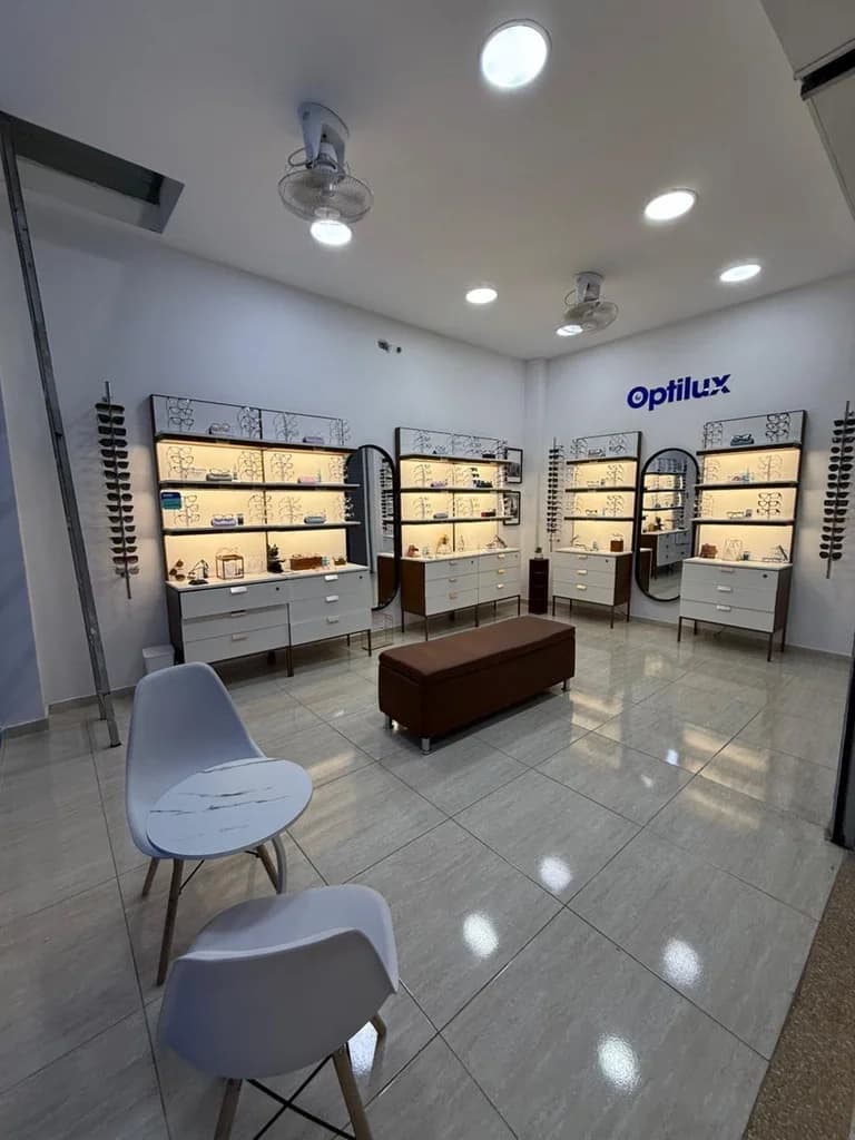 Perspectiva general de la tienda Optilux Valledupar, área de confort para pacientes y exhibidores de lentes.